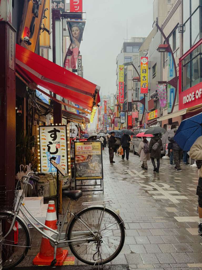 A pedestrian street in Tokyo Japan in the rain with a bike parked at a shop