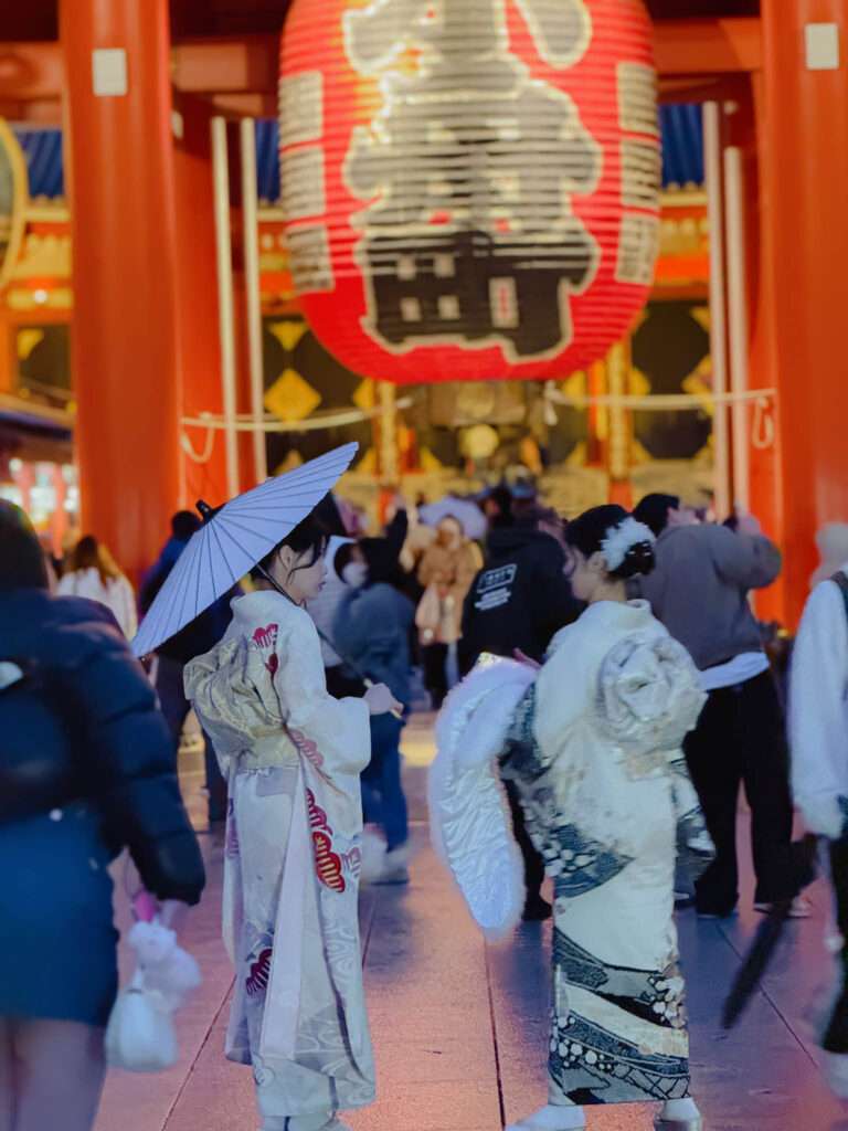 Two women in traditional Japanese clothing in front of a temple entrance