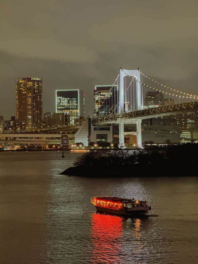 The riverfront of the Odaiba neighborhood in Tokyo faces a large bridge and the rest of the city