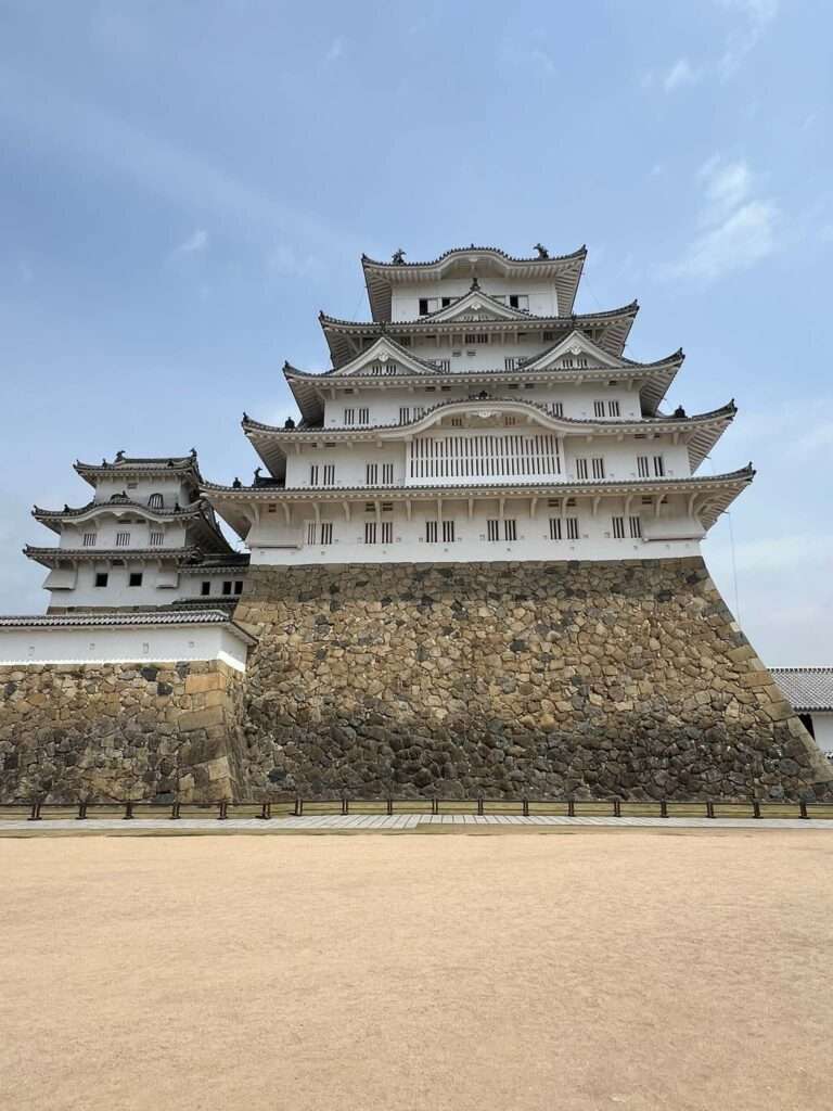 A large Japanese castle with a sandy landscape in front