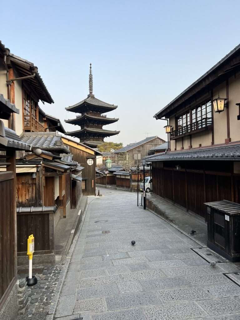 An old pedestrian street in Kyoto Japan lined with wooden buildings with a pegoda at the end of the street