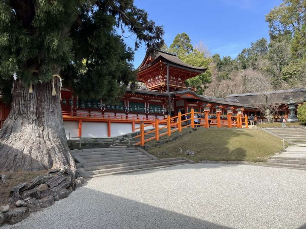 A red, white, and wood temple among a forest in Nara
