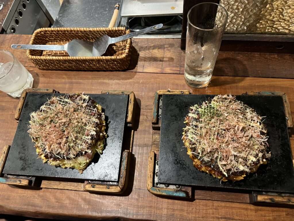 Two plates each with an Okonomiyaki, a savory Japanese pancake
