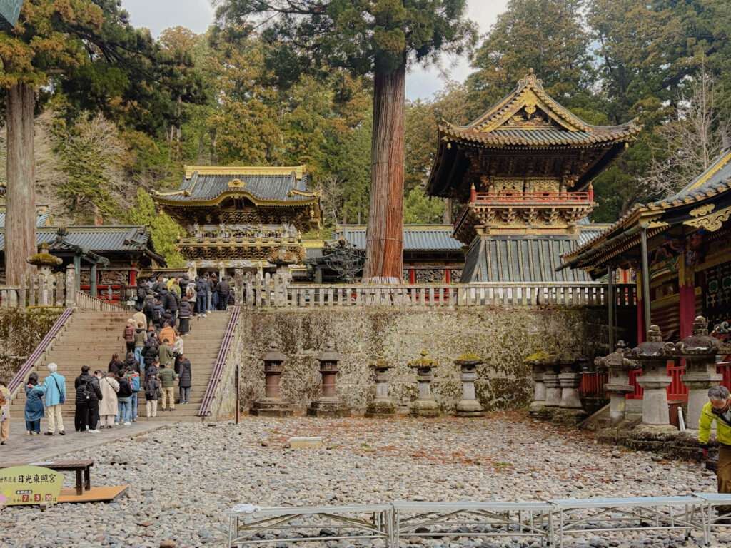 A line of people standing in line to enter a Japanese temple in the forest for a day trip to Nikko