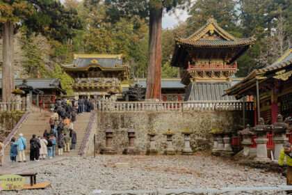 A line of people standing in line to enter a Japanese temple in the forest for a day trip to Nikko
