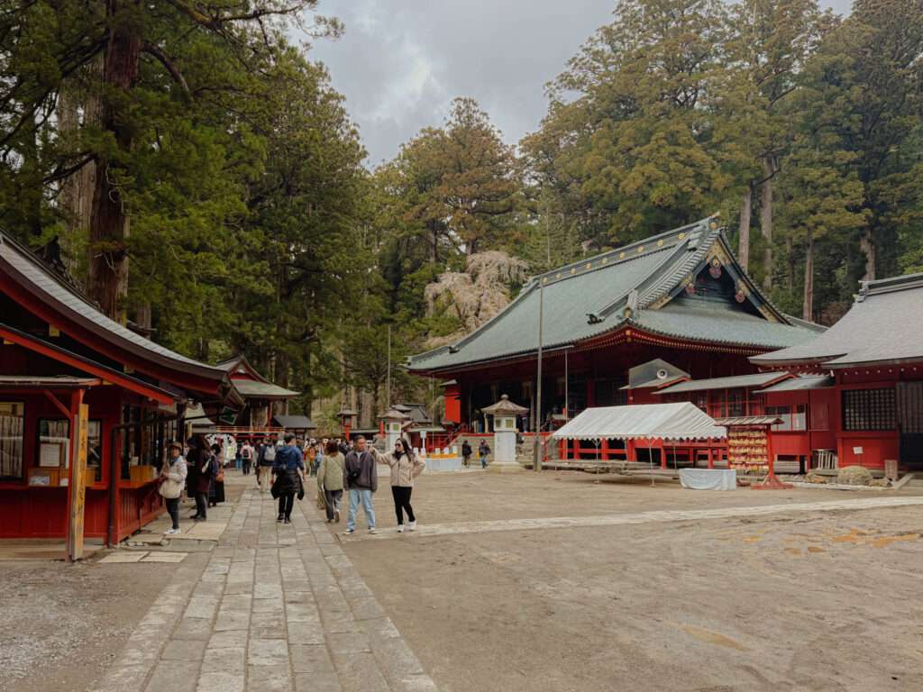A plaza surrounded by red temple buildings as part of the Futarasan shrine in Nikko