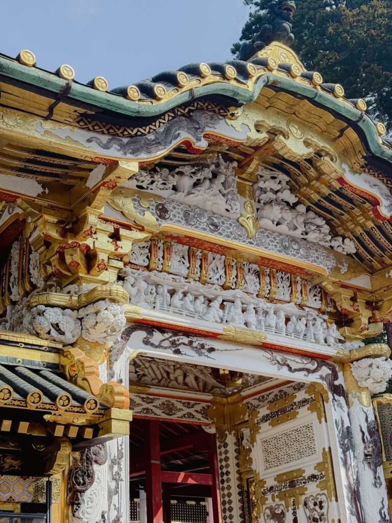 The heavily decorated gate of Toshogu Shrine in Nikko full of white and gold carvings