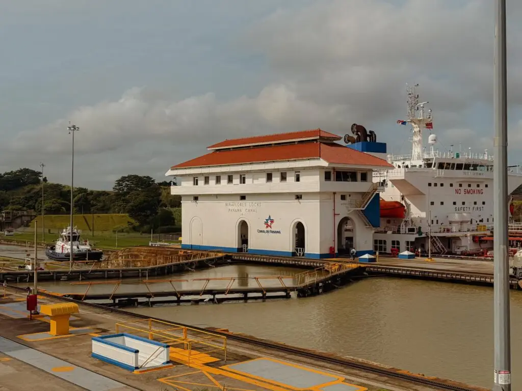 A cargo ship in the Miraflores lock chamber with the white Canal de Panama control building in the foreground, Panama Canal
