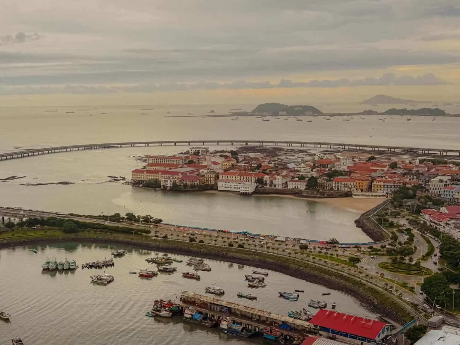 Aerial view of the Casco Viejo peninsula surrounded by water with fishing boats in the foreground and ships anchored in the Pacific beyond — Panama City travel guide