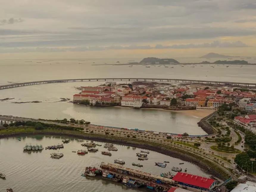 Aerial view of the Casco Viejo peninsula surrounded by water with fishing boats in the foreground and ships anchored in the Pacific beyond — Panama City travel guide