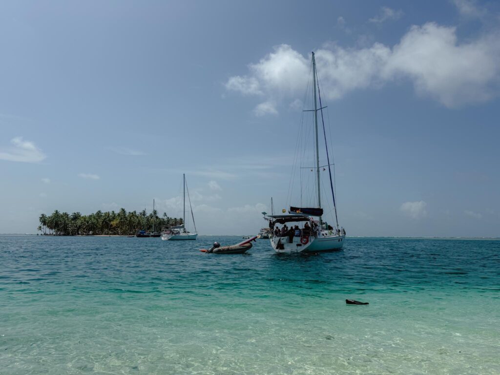 Sailboat anchored in clear turquoise water off a small palm-fringed island in the San Blas archipelago, Guna Yala, Panama