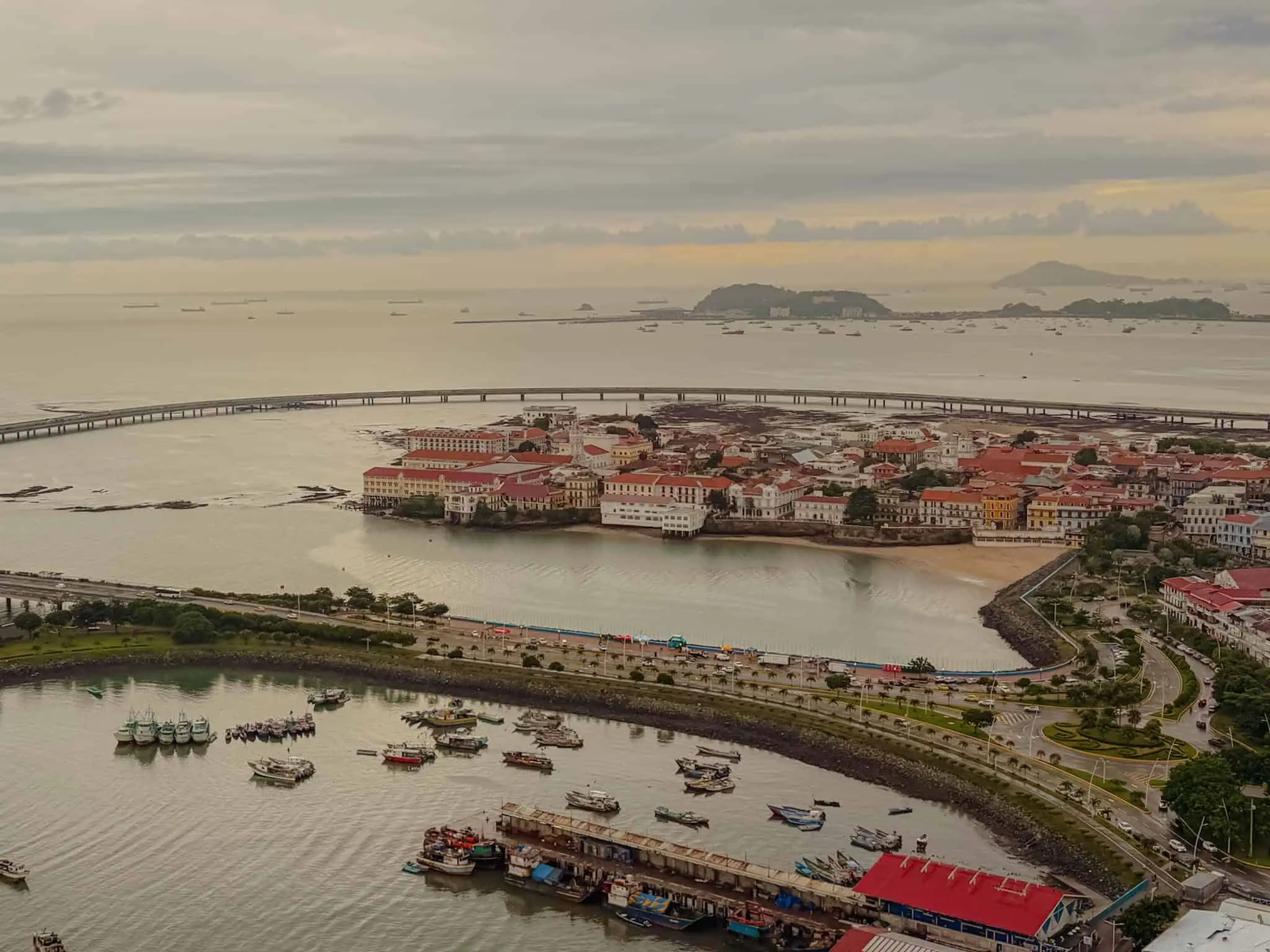 Aerial view of the Casco Viejo peninsula surrounded by water with fishing boats in the foreground and ships anchored in the Pacific beyond — Panama City travel guide