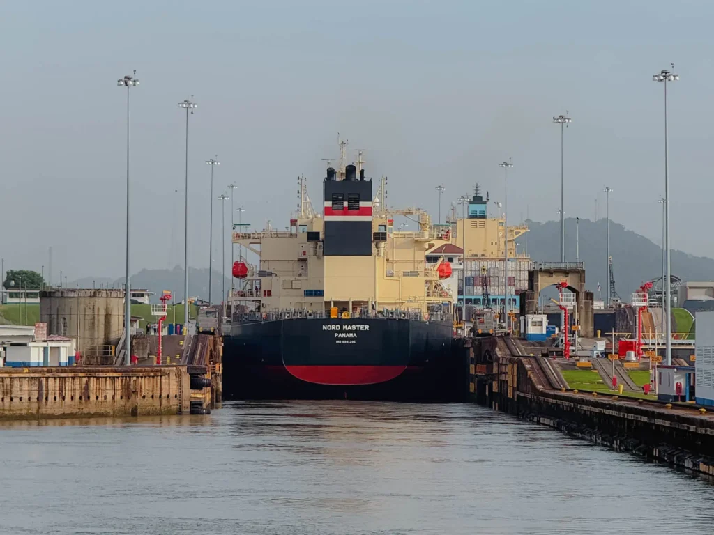 Cargo ship Nord Master entering a Panama Canal lock chamber viewed from water level with lock walls on either side -- Panama Canal full transit