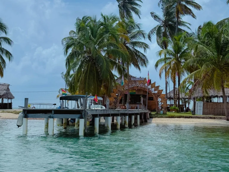 Wooden dock and open-air bar on a San Blas island surrounded by palm trees and turquoise water, Guna Yala, Panama -- day trips from Panama City