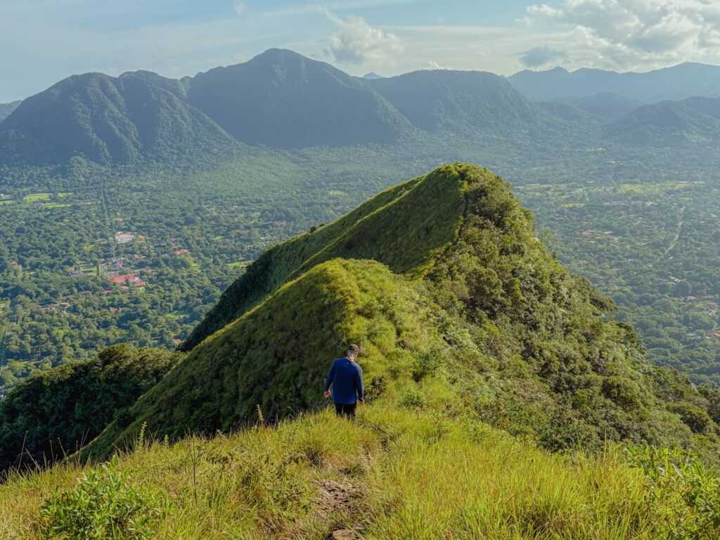 Hiker on the Cerro Cara Iguana trail above Valle de Anton with the crater valley and surrounding mountains visible below, Panama -- day trips from Panama City