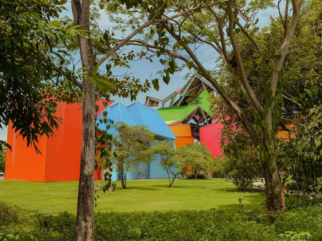 The Biomuseo's colorful angular exterior seen through tropical trees on the Amador Causeway — Biomuseo Panama