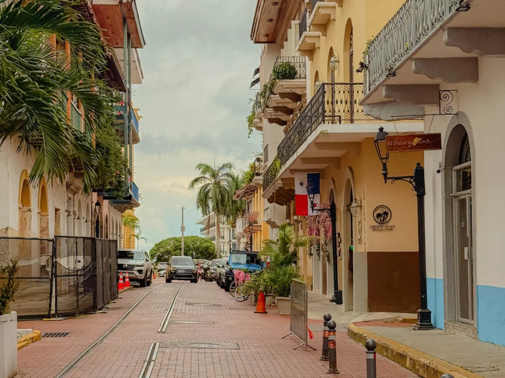 A cobblestone street in Casco Viejo with colonial facades and the Panamanian flag, looking toward the bay — Casco Viejo Panama City