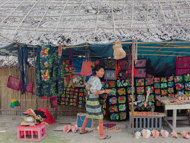 Guna woman in traditional dress arranging mola textiles at a market stall in San Blas - Guna Yala Panama responsible travel