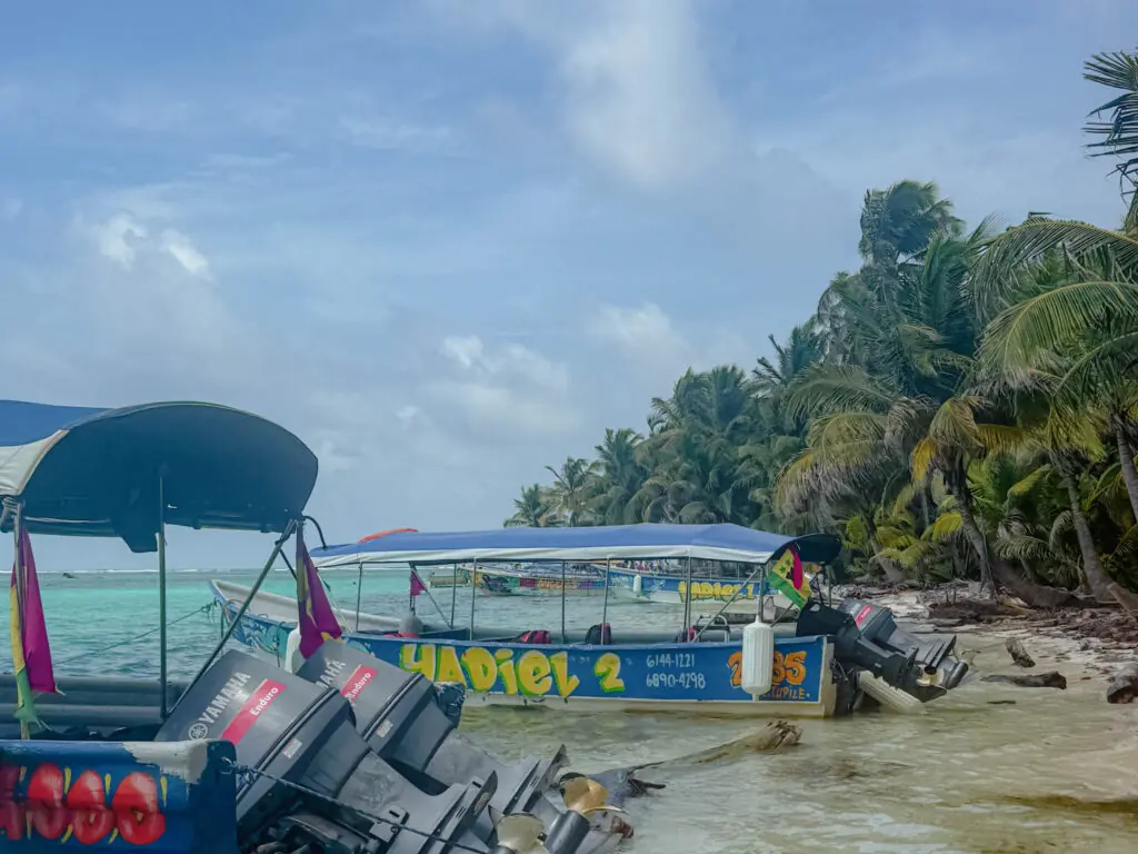 Colorful local water taxi boats beached on a San Blas island shoreline with palm trees behind - getting to San Blas Panama