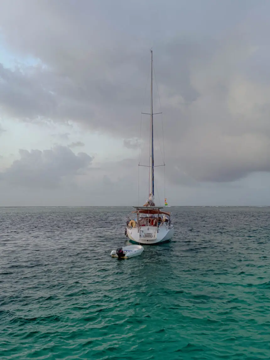 Single sailboat anchored on open turquoise water in San Blas with an overcast sky - sailing charter San Blas Islands