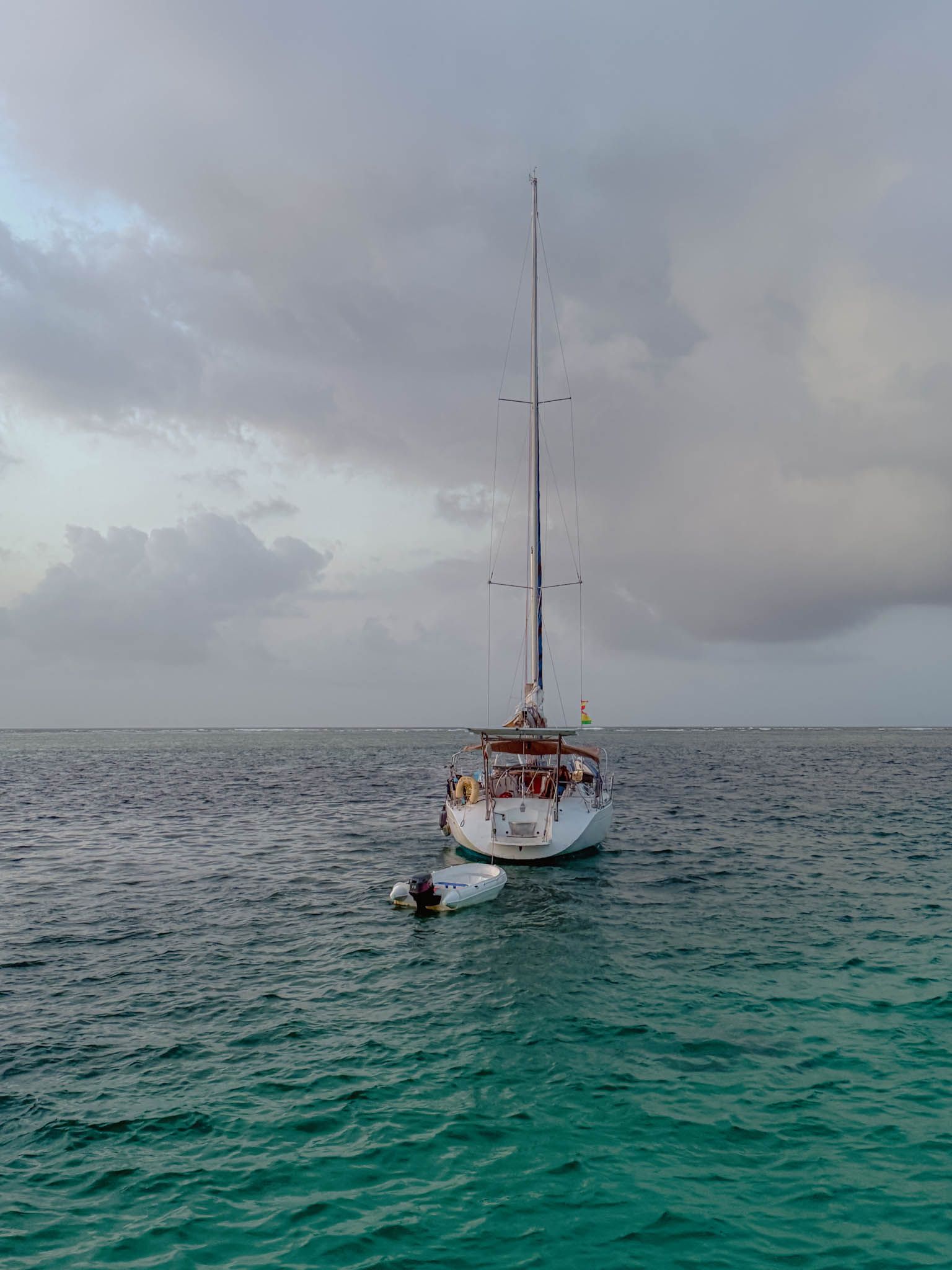 Single sailboat anchored on open turquoise water in San Blas with an overcast sky - sailing charter San Blas Islands