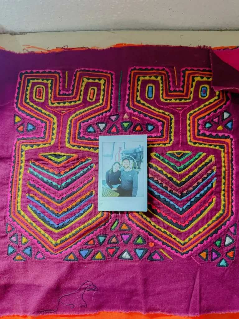 Close-up of a traditional Guna mola textile showing intricate reverse-appliqué geometric patterns in red pink and orange - Guna Yala Panama