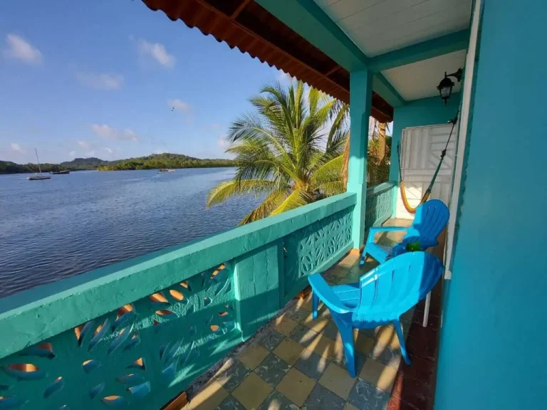 Teal balcony with blue chair and hammock at Casa Congo overlooking Portobelo bay with sailboats and palms -- Portobelo Panama