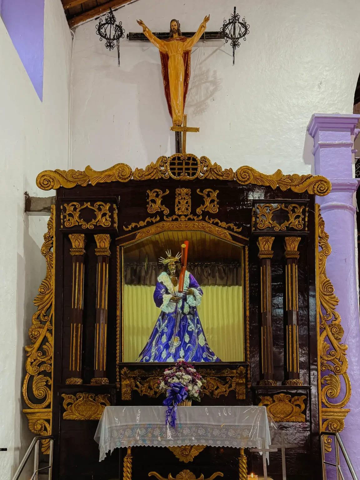 The Black Christ of Portobelo in its ornate gold altar niche inside the Church of San Felipe dressed in a blue robe -- Portobelo Panama