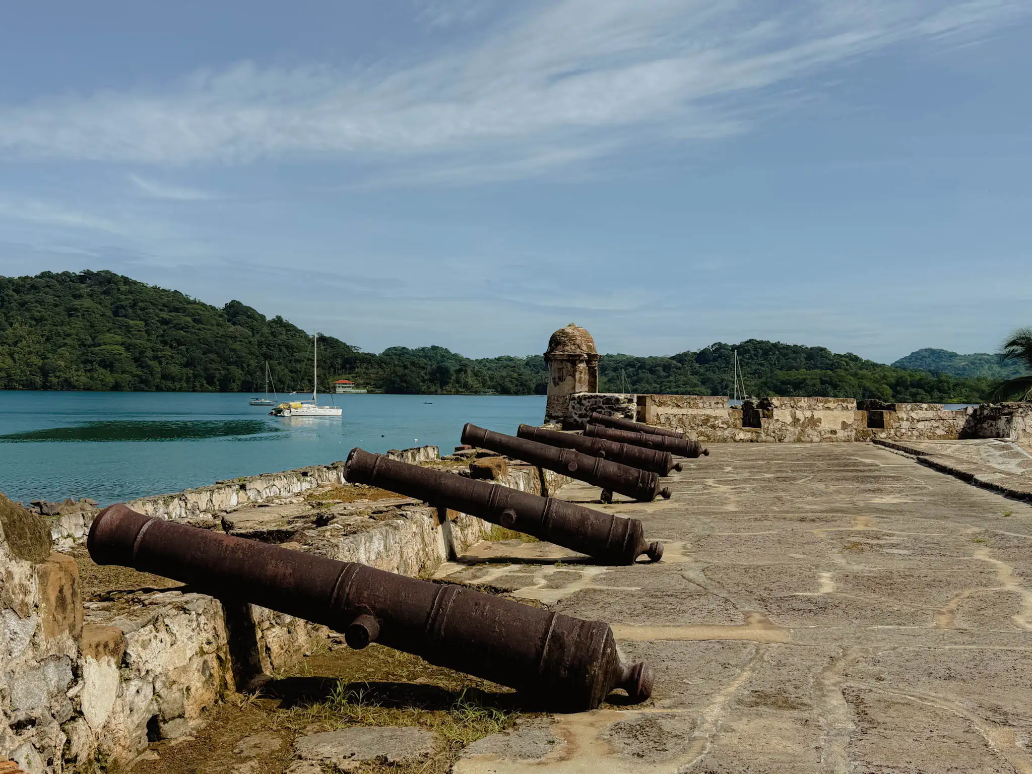 Iron cannons on the ramparts of Fort San Felipe overlooking Portobelo bay and jungle hills -- Portobelo Panama