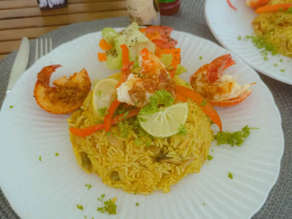 A plate of saffron rice topped with whole shrimp, lime, and fresh herbs served on the deck of a sailboat -- food on San Blas sailing trip fresh seafood
