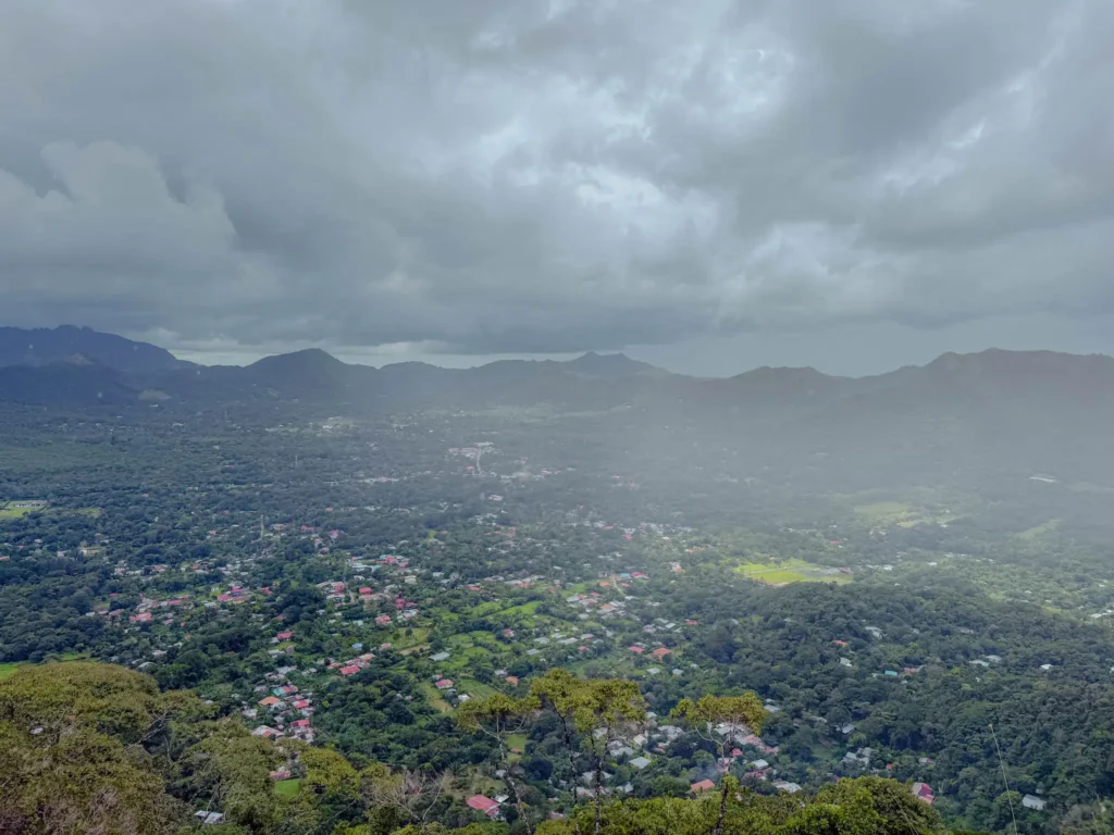 Aerial view of the Valle de Anton volcanic crater filled with the town below, ringed by mountains and heavy cloud cover - Valle de Anton hiking