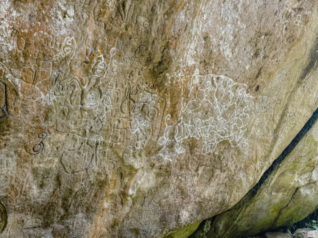 Pre-Columbian petroglyphs carved into the large rock face of La Piedra Pintada with white chalk-like symbols and figures still clearly visible - Valle de Anton hiking