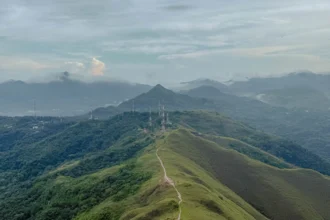 Aerial view of the Valle de Anton crater ridgeline with a trail running along the spine and mist-covered mountains in the background -- Valle de Anton Panama