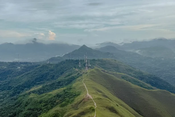 Aerial view of the Valle de Anton crater ridgeline with a trail running along the spine and mist-covered mountains in the background -- Valle de Anton Panama
