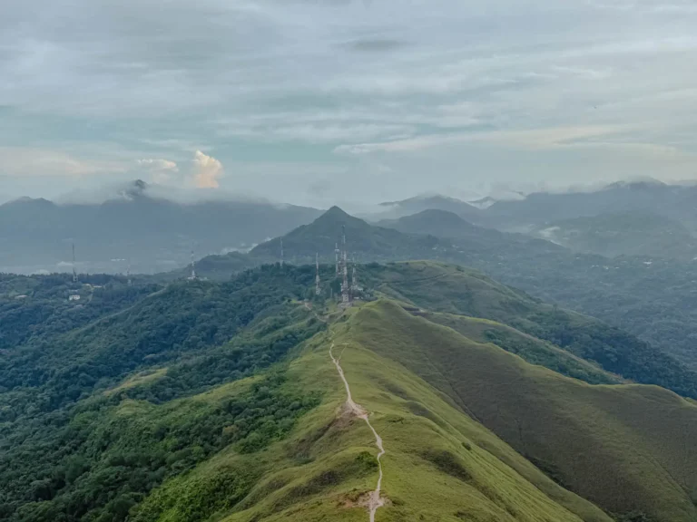 Aerial view of the Valle de Anton crater ridgeline with a trail running along the spine and mist-covered mountains in the background -- Valle de Anton Panama
