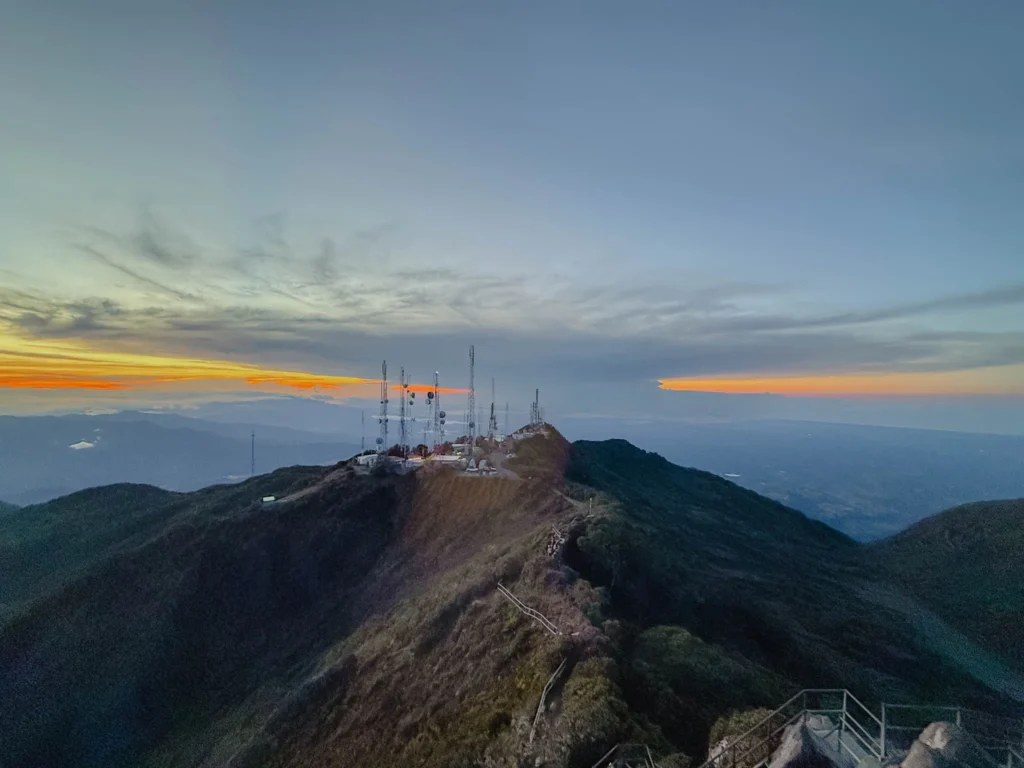 Sunrise over the antennae station at the summit of Volcan Baru with mountains and ocean horizon visible - Volcan Baru hike