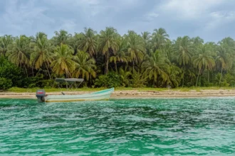 Best beaches in Bocas del Toro Panama: boat on the sand and vivid turquoise water at Cayos Zapatilla in the National Marine Park