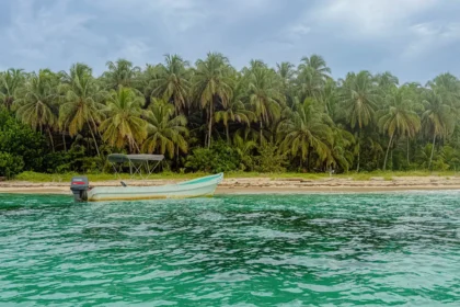 Best beaches in Bocas del Toro Panama: boat on the sand and vivid turquoise water at Cayos Zapatilla in the National Marine Park