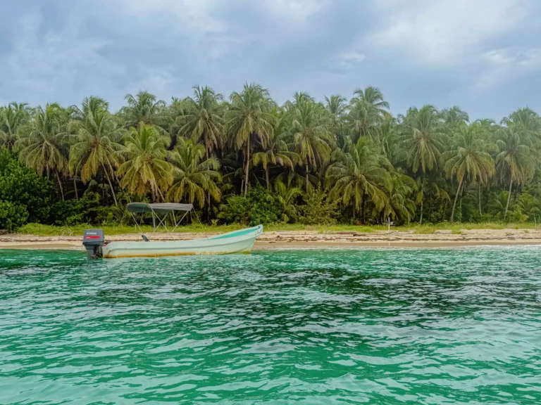 Best beaches in Bocas del Toro Panama: boat on the sand and vivid turquoise water at Cayos Zapatilla in the National Marine Park