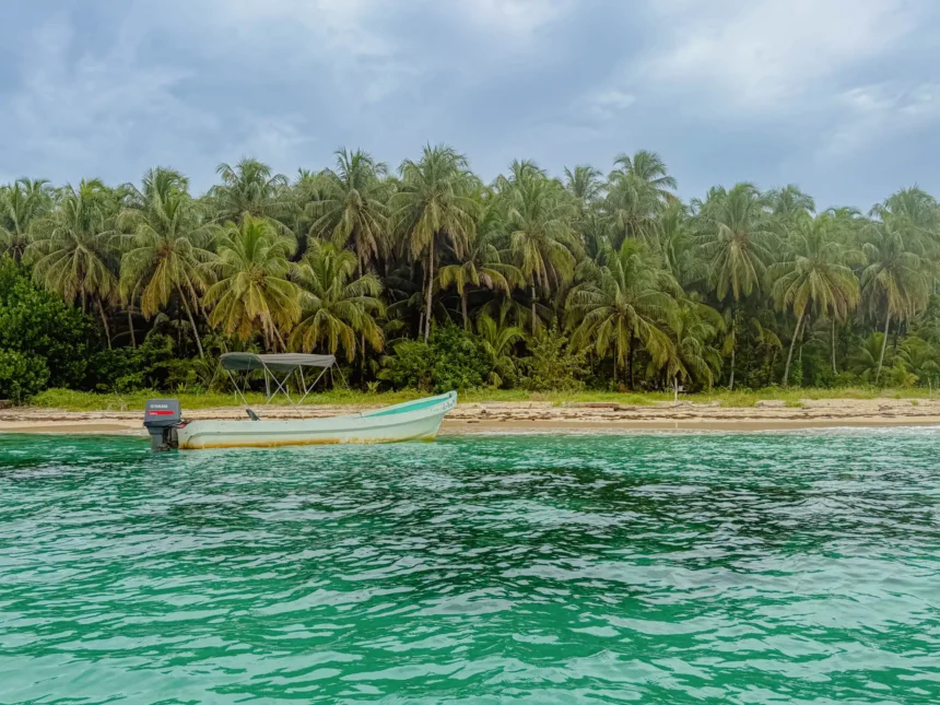 Best beaches in Bocas del Toro Panama: boat on the sand and vivid turquoise water at Cayos Zapatilla in the National Marine Park
