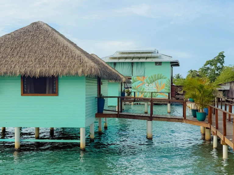 Turquoise over-water bungalows with thatched roofs at Sol Bungalows, Bocas del Toro