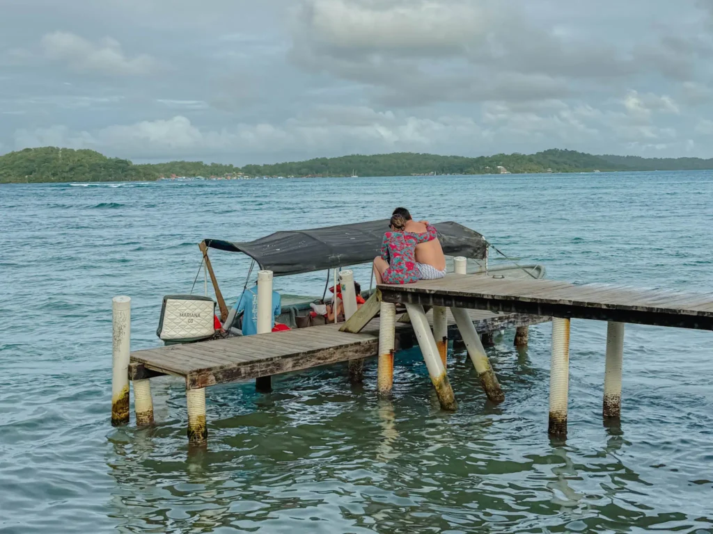Travelers boarding a covered water taxi from a weathered dock in Bocas del Toro