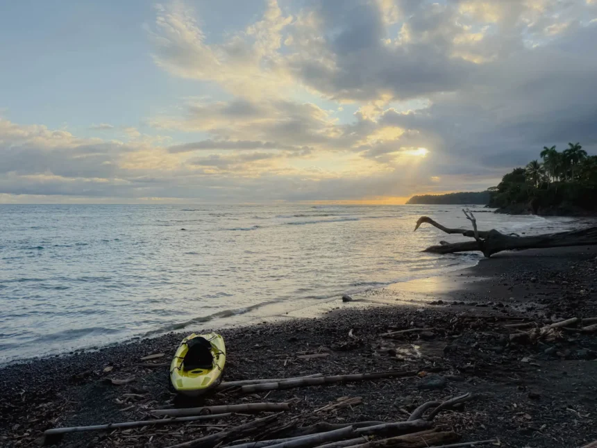 Yellow kayak resting on a dark sand beach at sunset in Santa Catalina, Panama