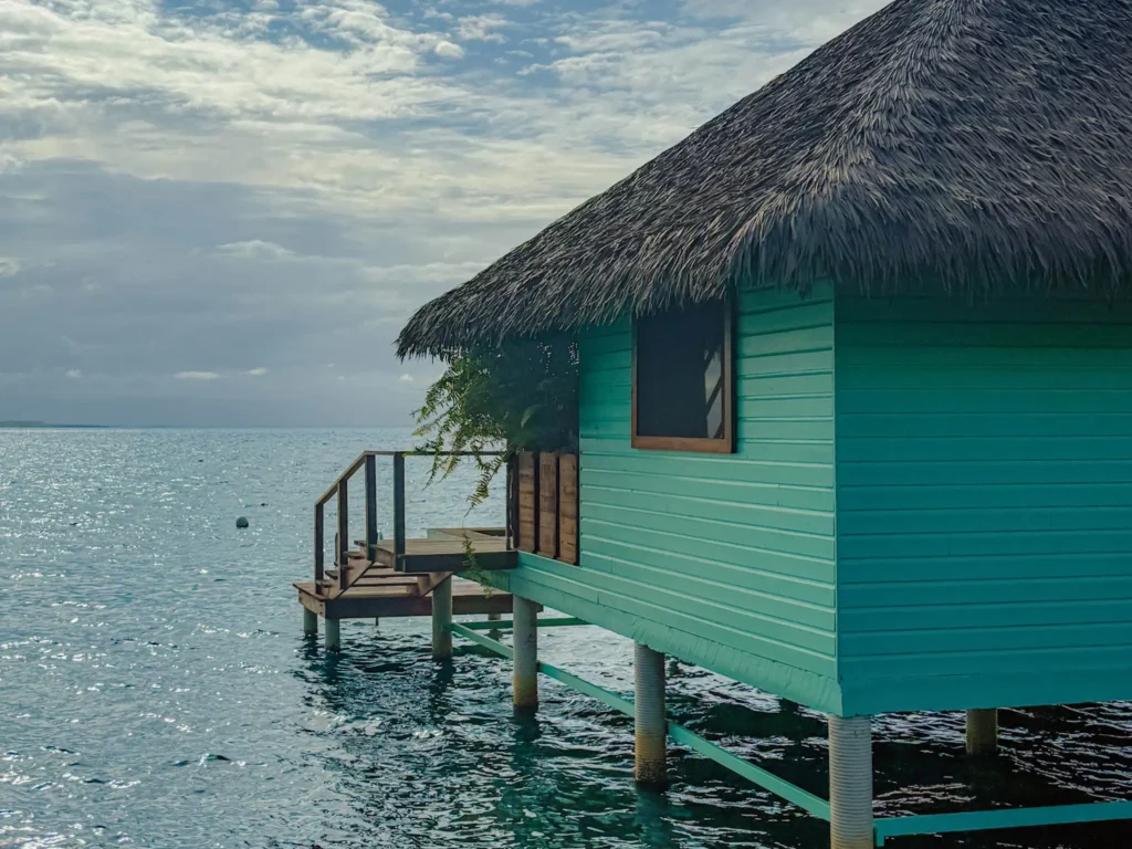 Turquoise thatched over-water bungalow on stilts on Isla Solarte in Bocas del Toro