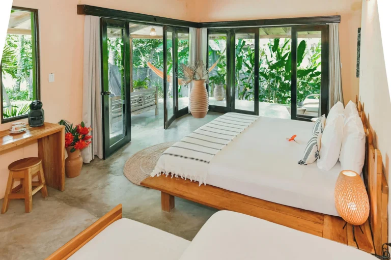 Boho style room with folding glass doors opening onto a tropical garden and hammock at Villa Coco in Santa Catalina, Panama