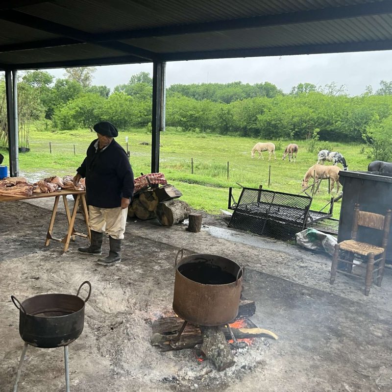 Argentina – Food and Drinks – asado A few people dressed in traditional Argentine clothing prepping food for an asado barbecue - Argentina food and drinks