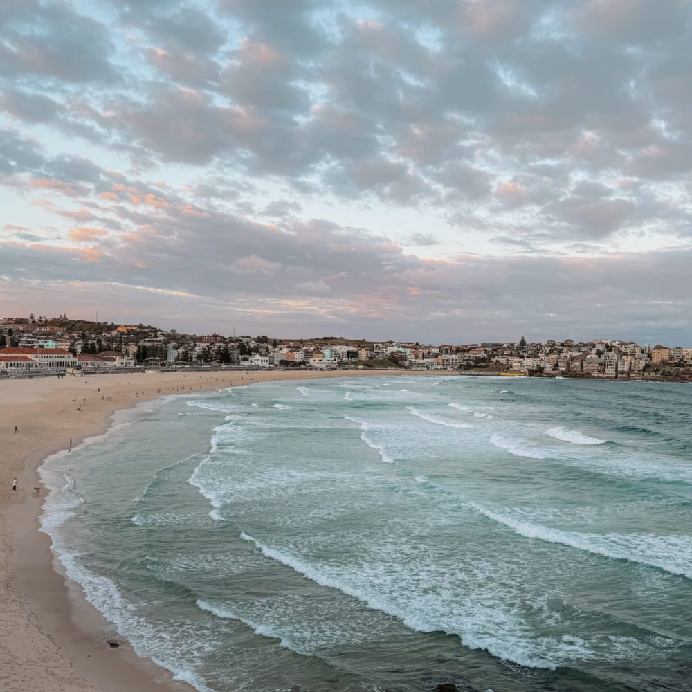 Sunset over a large beach with buildings at the coastline - Sydney itinerary