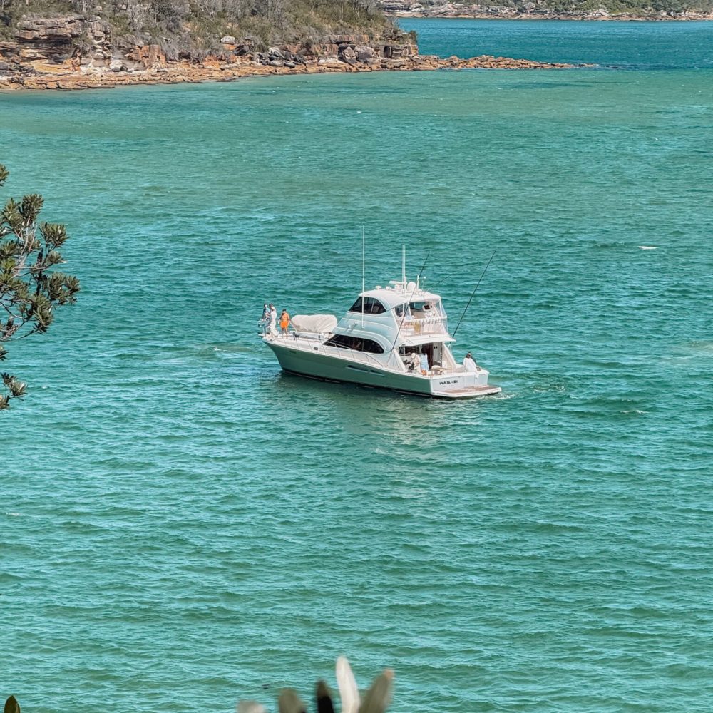 A boat anchored in a cove of turquoise blue water - Sydney itinerary