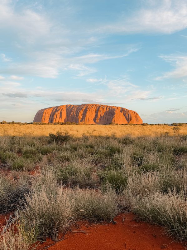 Australia_Uluru_Kata Tjuta_Valley of the Winds_Kings Canyon-17 A large red rock in the desert with brush at sunset and one of the top 10 things to do in Australia