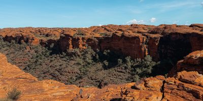 The view overlooking a cliff into a canyon filled with low brush - what to do in uluru